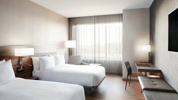 Camera d'albergo con due letti, una scrivania e una sedia.
