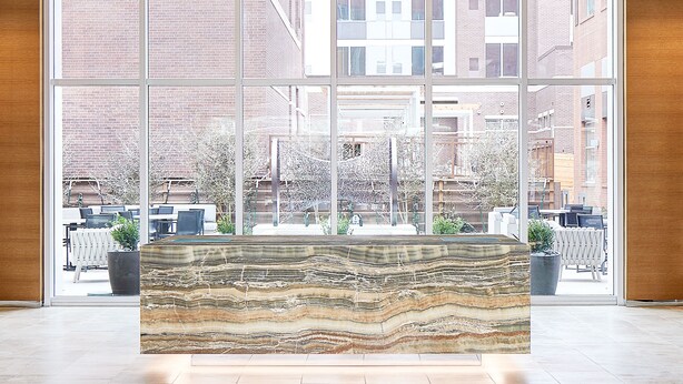A modern interior with large windows, a central art piece, and a view of the outside buildings.