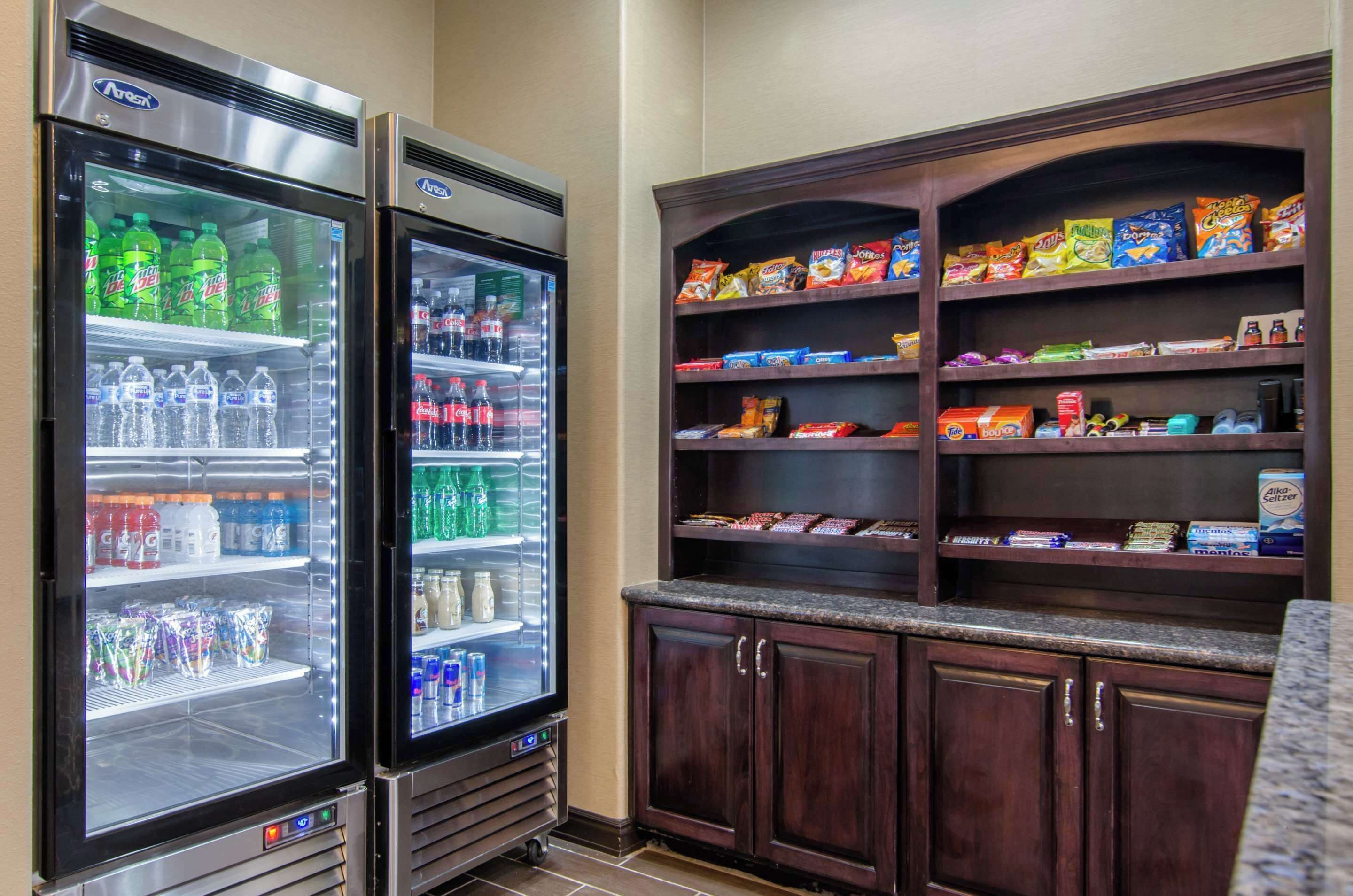Dos dispensadores de bebidas con diversas opciones, una estantería para snacks y un armario con cajones.