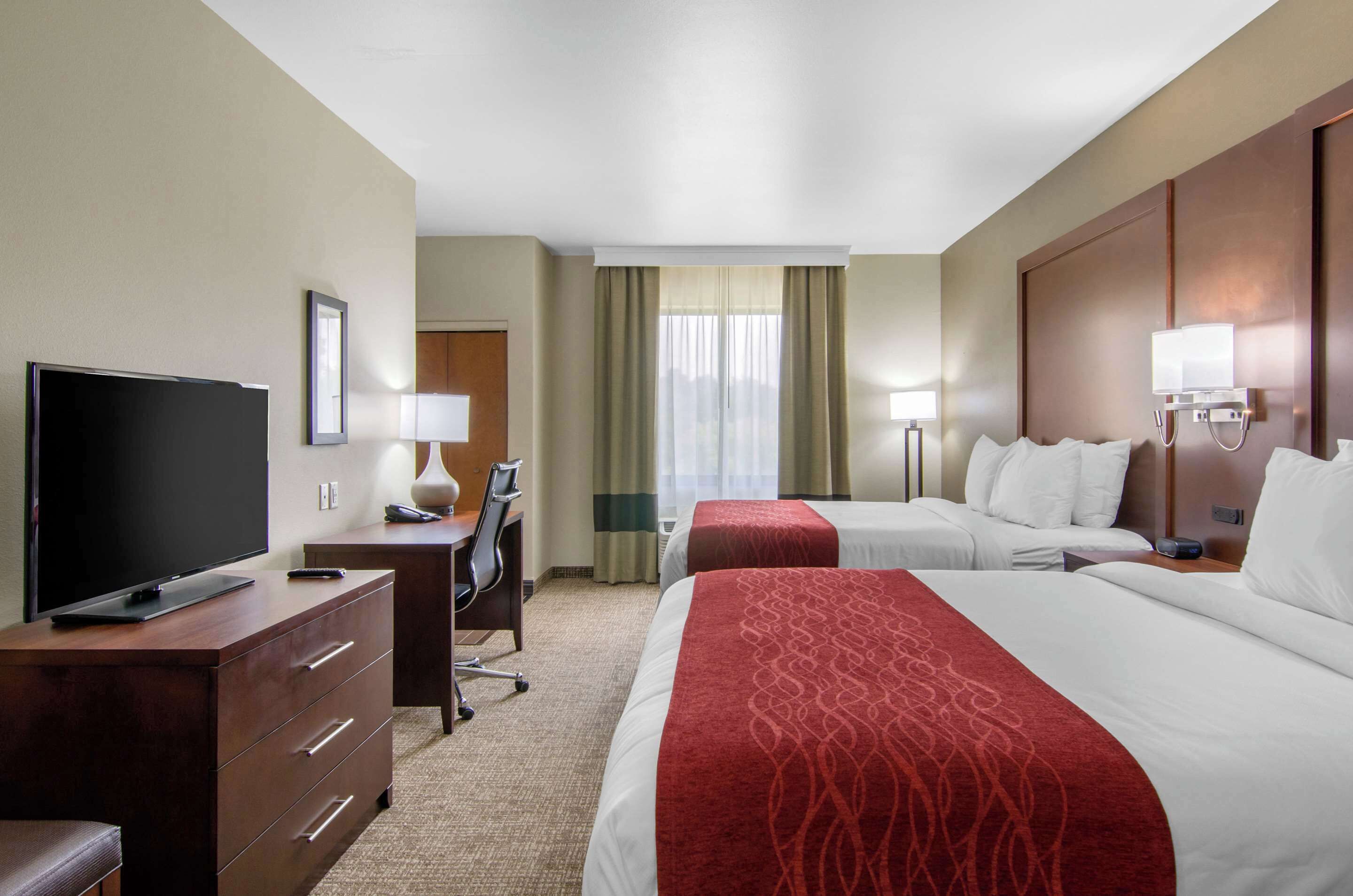 Habitación de hotel con dos camas, televisión, escritorio y silla.