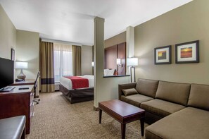 A hotel room with a bed, a sofa, a desk, a TV, and two framed pictures on the wall. - Comfort Inn & Suites Shawnee - Kansas City (Shawnee)