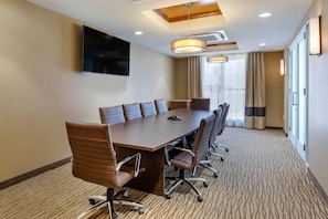 A conference room with a long table, multiple chairs, a flat-screen TV, ceiling lights, and a window with curtains. - Comfort Inn & Suites Edgewood (Edgewood)