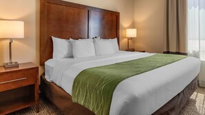 A hotel room with a large bed, two bedside tables, a green throw blanket, and a window with curtains. - Comfort Inn & Suites Edgewood (Edgewood)