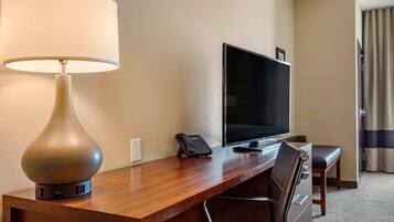 A hotel room with a wooden desk, a television, a telephone, and a chair.