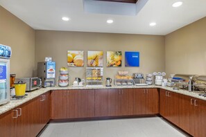 Ein Frühstücksbuffet mit verschiedenen Speisen, einer Kaffeestation und einem Schild, das die Verfügbarkeit von Joghurt anzeigt.