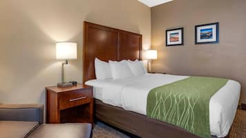 A hotel room with a bed, two bedside lamps, a nightstand, a chair, and two framed pictures on the wall.
