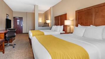 A hotel room with two beds, a desk, a chair, and a television.