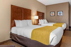 A hotel room with two beds, a wooden headboard, a bedside table with a lamp, and two framed pictures on the wall. - Comfort Inn & Suites Edgewood (Edgewood)