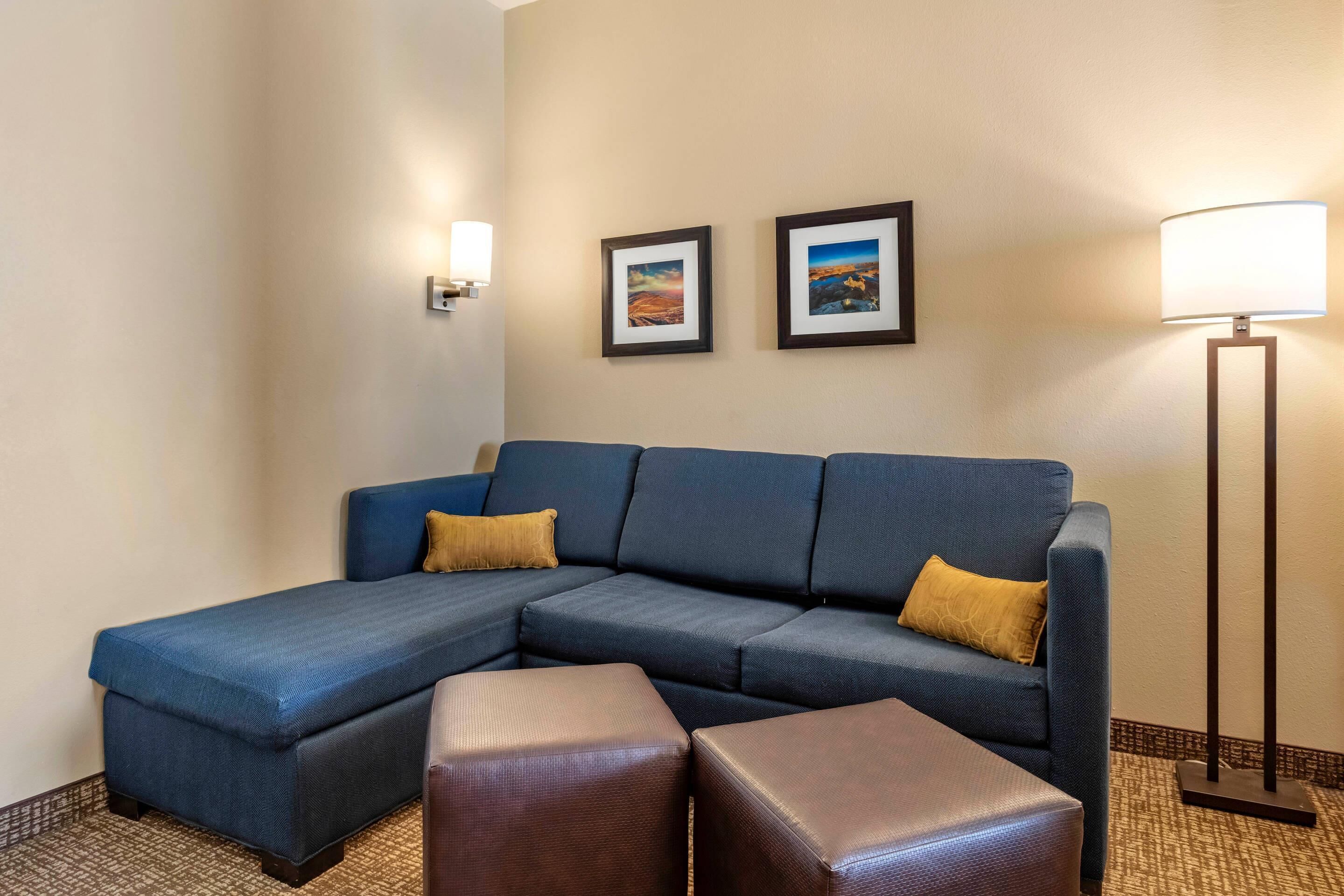 A hotel room with a sectional sofa, two side tables, and two framed pictures on the wall.