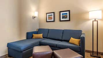 A hotel room with a sectional sofa, two side tables, and two framed pictures on the wall.