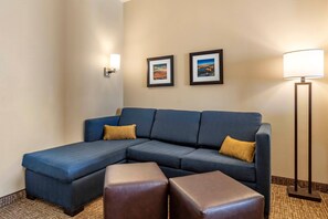 A hotel room with a sectional sofa, two side tables, and two framed pictures on the wall. - Comfort Inn & Suites Edgewood (Edgewood)