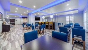 A modern hotel lobby with blue and wooden furniture, a kitchen area, and a large TV screen. - Comfort Inn & Suites Oklahoma City South I-35 (Oklahoma City)