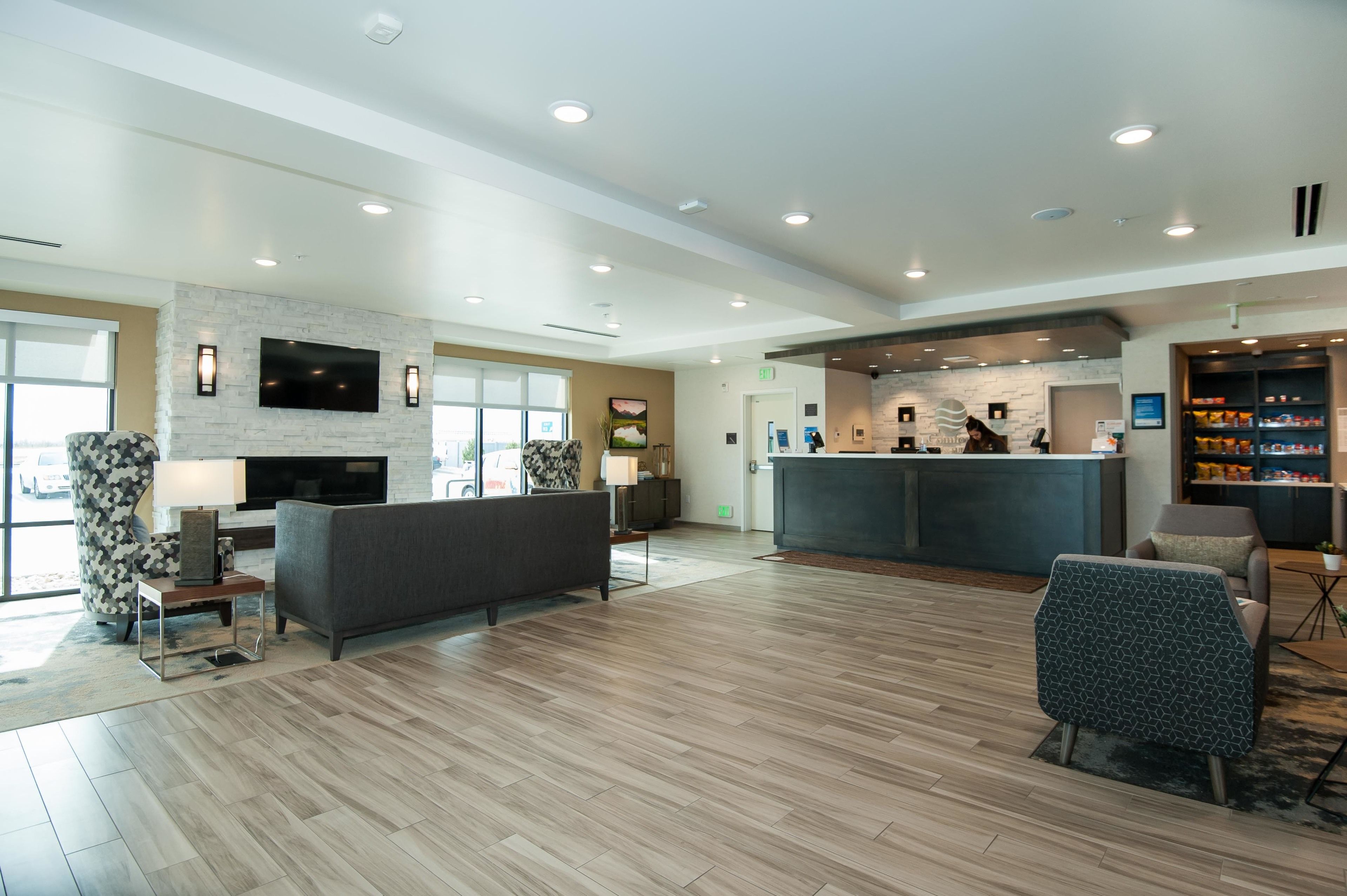A spacious lobby with a modern fireplace, comfortable seating, a reception desk, and a well-stocked bar area.