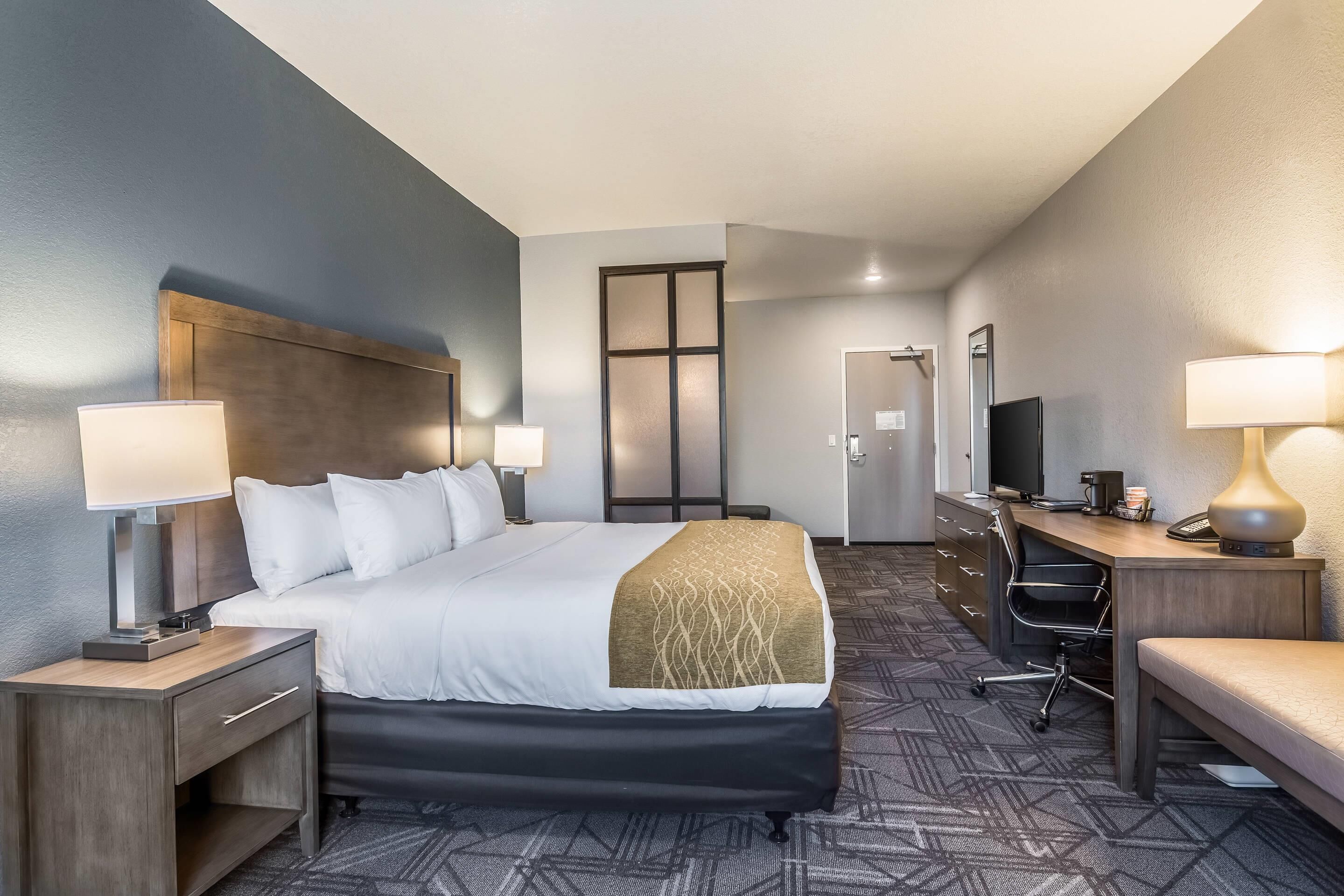 Una habitación de hotel con una cama grande, un escritorio con una computadora y un televisor.