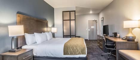 Una habitación de hotel con una cama grande, un escritorio con una computadora y un televisor.