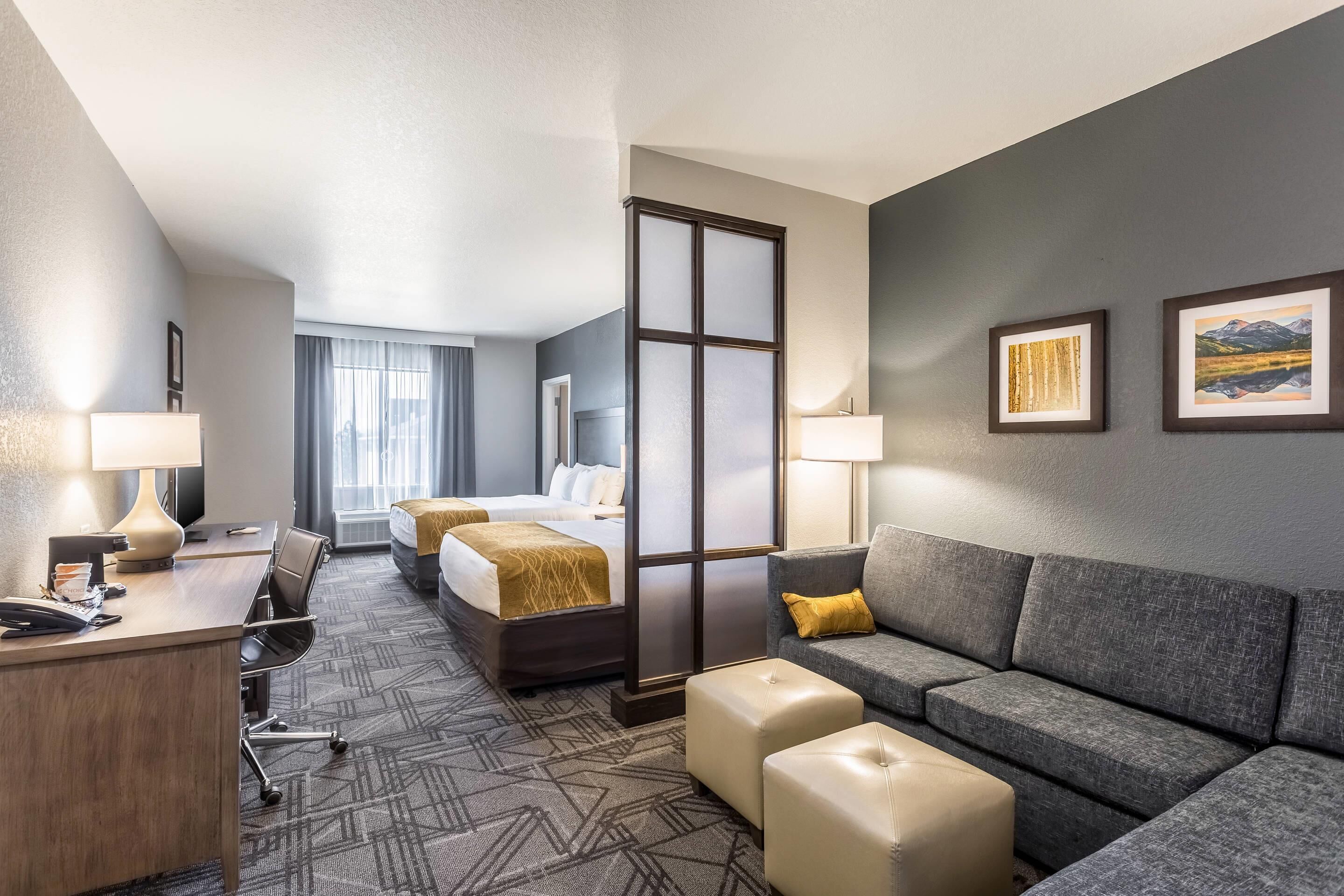 Une chambre d’hôtel avec un lit, un bureau, un canapé et une grande fenêtre.