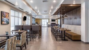 A modern restaurant with hexagonal tiled flooring, wooden and cushioned seating, pendant lighting, and a large window providing natural light. - Comfort Inn & Suites Salt Lake City Airport (Salt Lake City)