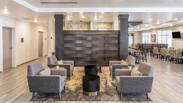 A spacious lobby with modern sofas, a central black accent wall, and a dining area in the background. - Comfort Inn & Suites Salt Lake City Airport (Salt Lake City)