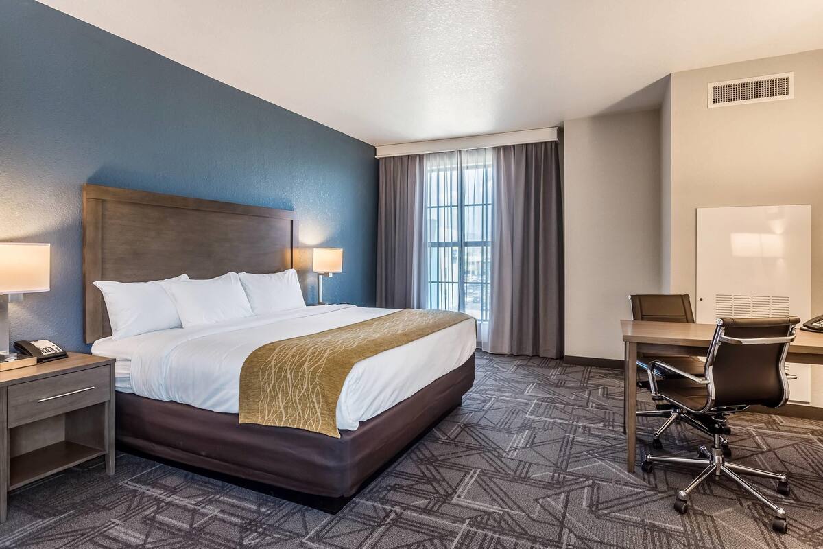 Une chambre d’hôtel avec un grand lit, un bureau et une chaise.