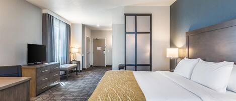 A hotel room with a large bed, a desk, a television, and a window with curtains.
