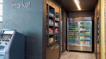 A self-service kiosk, refrigerated beverage dispensers, and a vending machine in a commercial area.