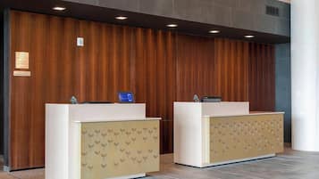 Un área de recepción con dos mostradores, un panel de madera en la pared y suelo de baldosas.