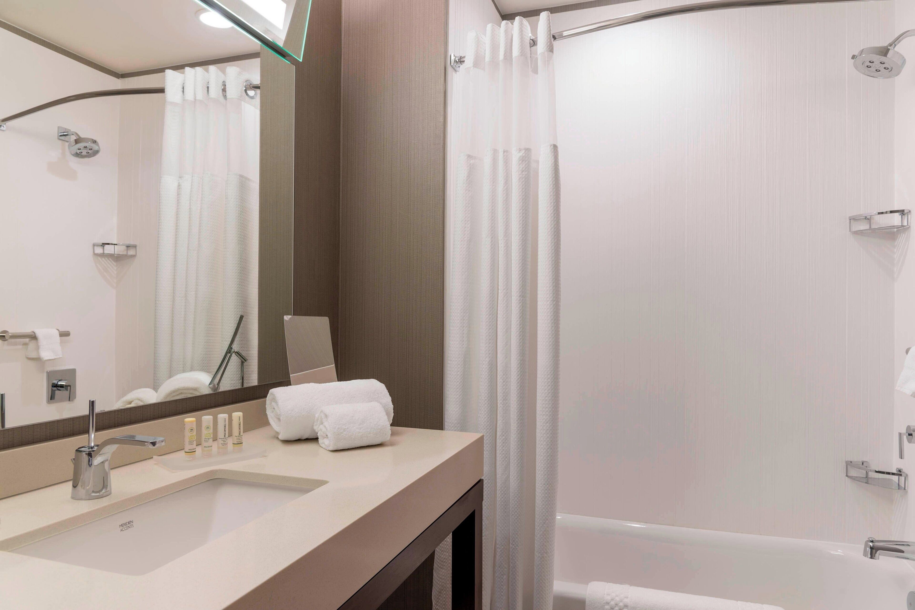 Ein modernes Badezimmer mit Waschbecken, Spiegel, Dusche und Badewanne.