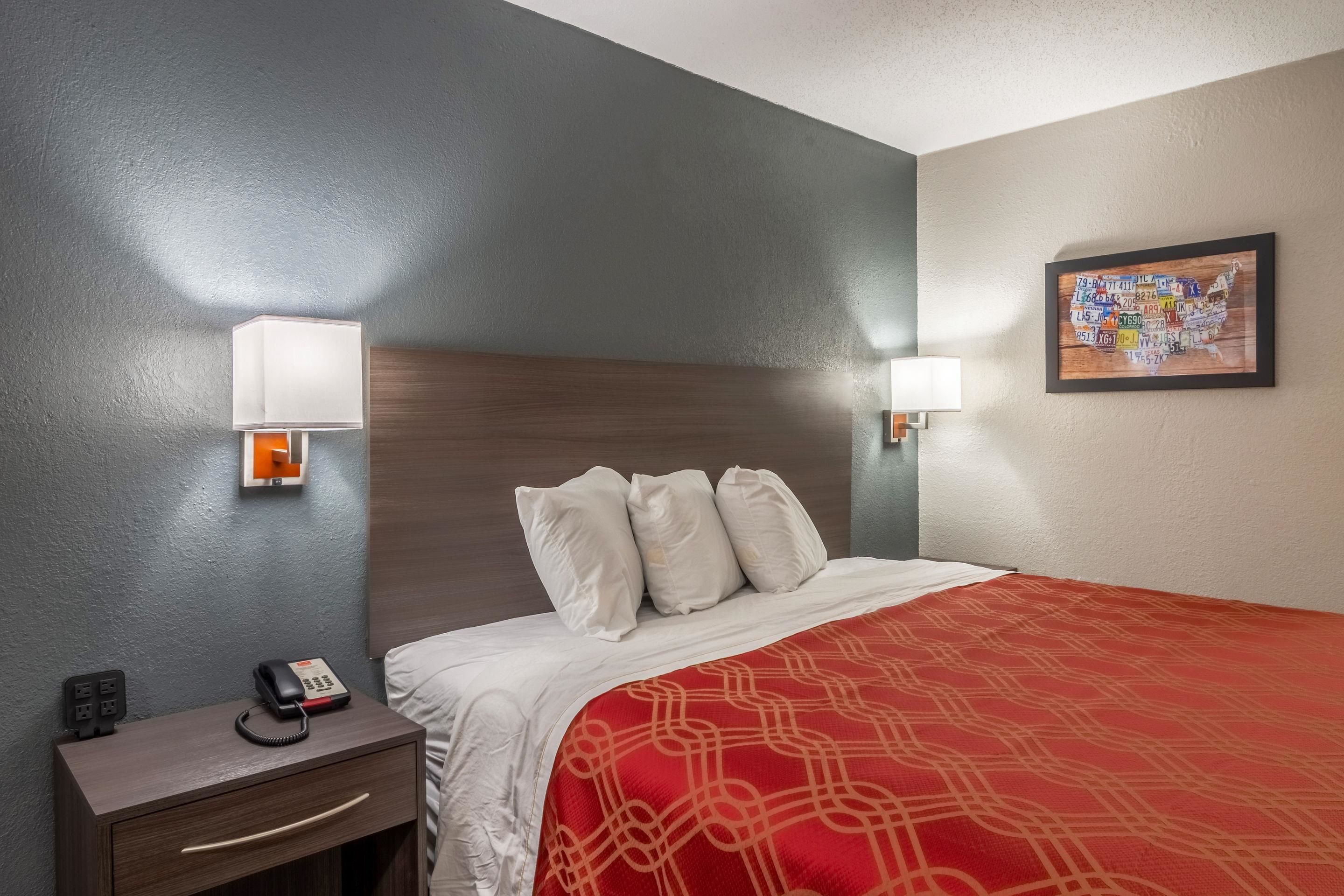 Een hotelkamer met een bed, bedlampjes, een telefoon en een kaart aan de muur.