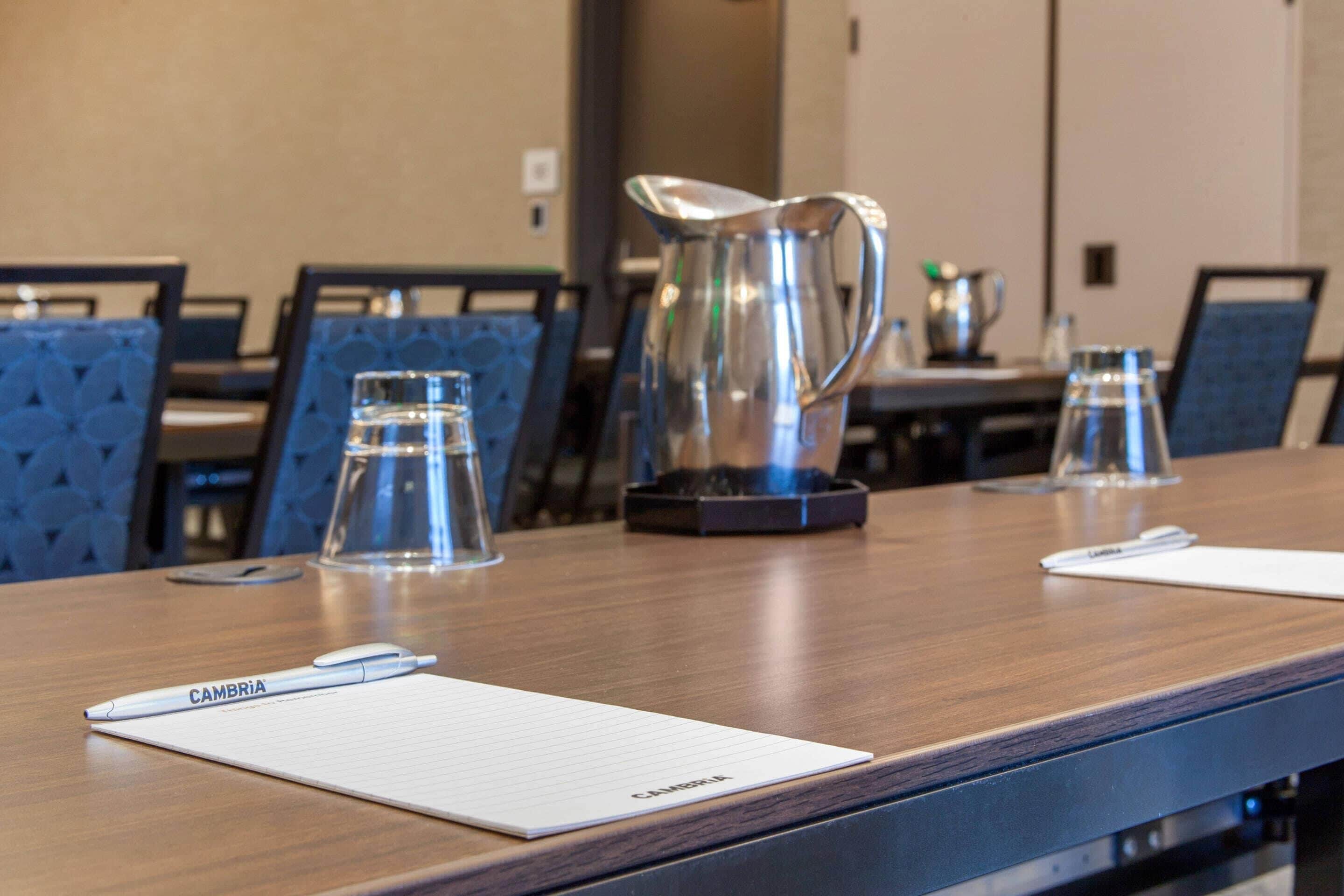 A conference table with a notepad, pen, and a silver pitcher.