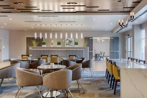 Eine moderne Hotelhalle mit Empfangstresen, Sitzgelegenheiten und einem großen Konferenztisch.