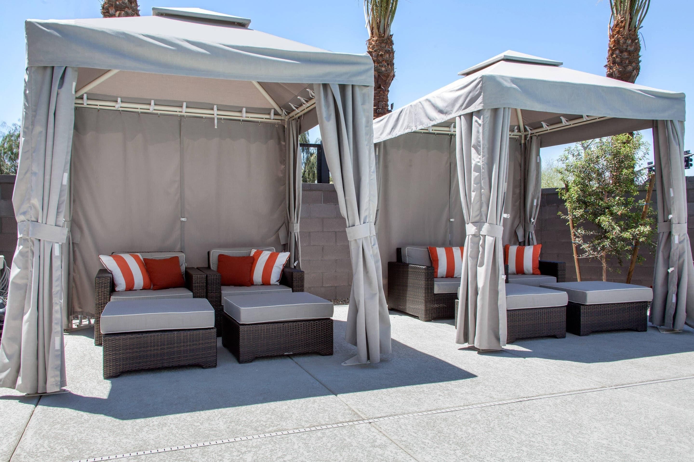 Two outdoor seating areas with canopies, cushioned sofas, and pillows.