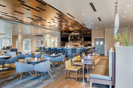 A modern bar area with a circular bar counter, seating arrangements, and a visible kitchen area.. Cambria Hotel Phoenix Chandler - Fashion Center