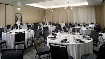 A conference room with round tables, chairs, and a chandelier.