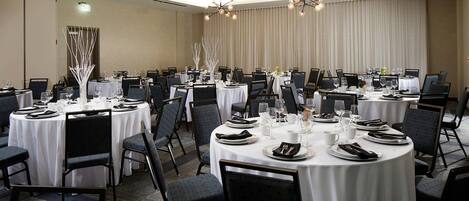 A conference room with round tables, chairs, and a chandelier.