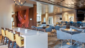 Un moderno hall de hotel con un mostrador de recepción de mármol, varias zonas de estar y una gran obra de arte abstracta en la pared.