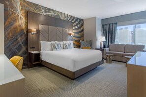 Een moderne hotelkamer met een groot bed, een bank, een bureau en uitzicht op de stad.