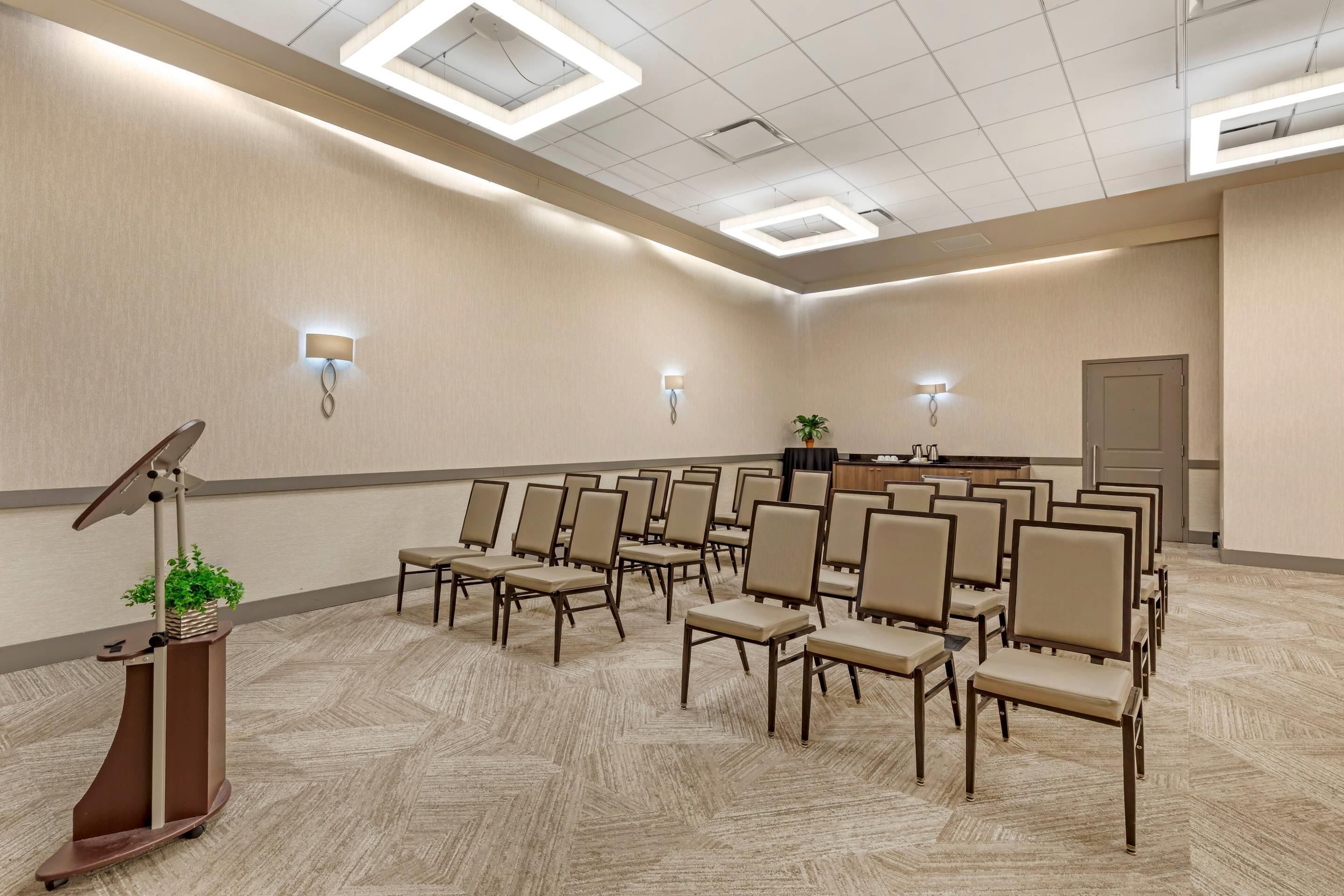 A conference room with rows of chairs, a podium, and a reception desk.