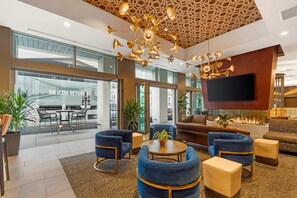 Een ruime lobby met een moderne kroonluchter, comfortabele zitplaatsen, een flatscreen-tv en een groot raam met uitzicht op de straat.