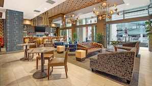 A modern hotel lobby with a bar area, seating arrangements, and large windows offering views of the city.
