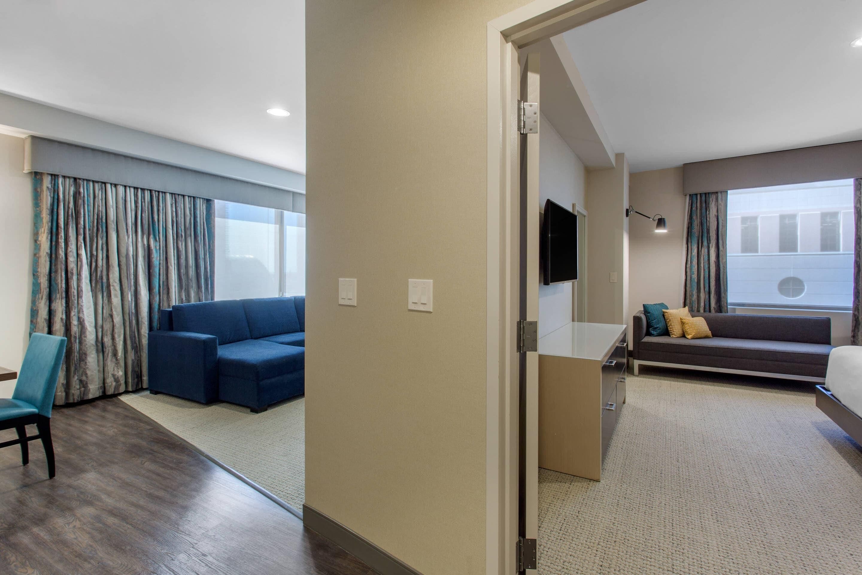 Una habitación de hotel con un ventanal grande, un sofá, una silla y una cama.