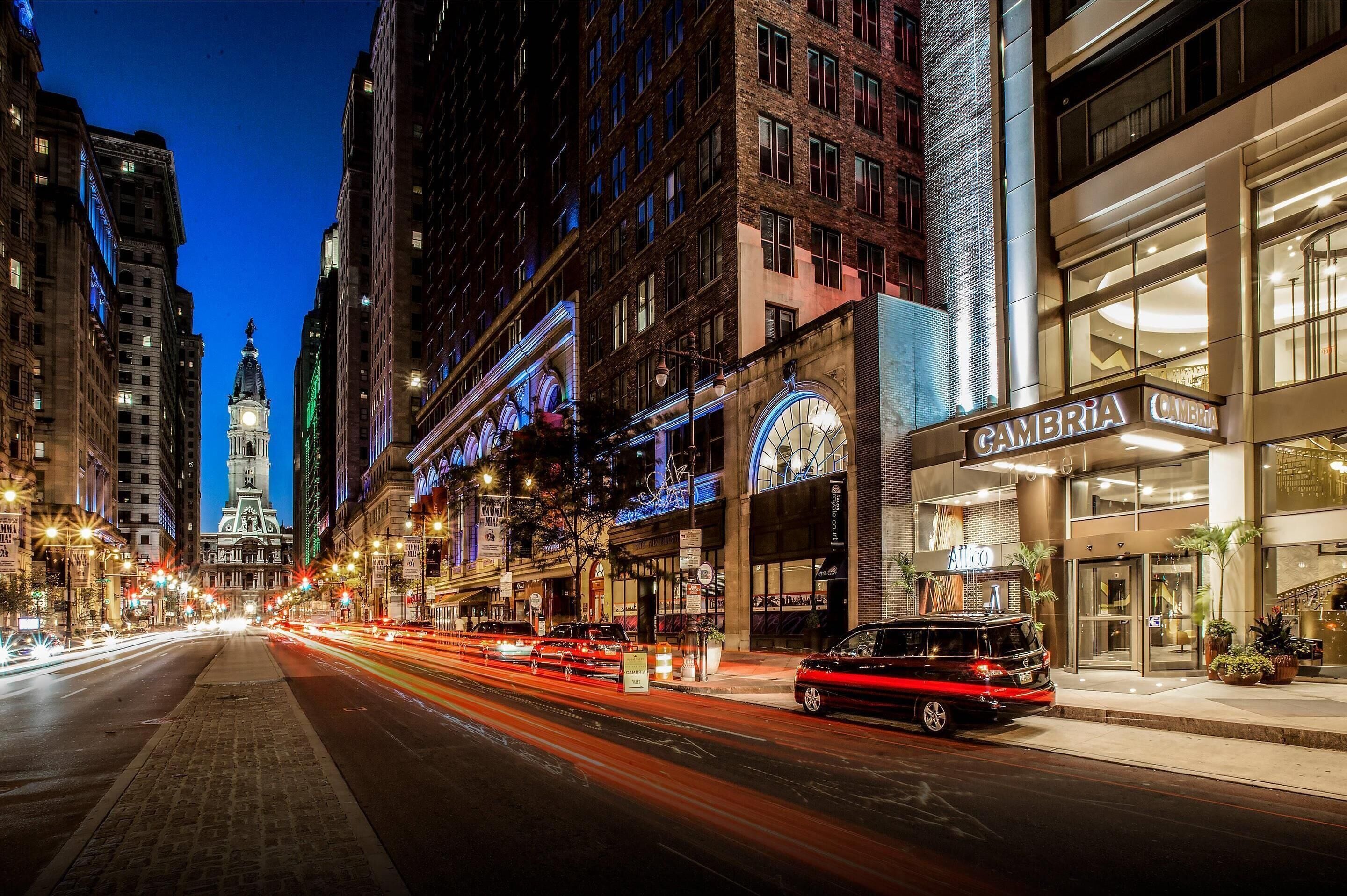 A nighttime city street with a building labeled "CAMBRIA" and a clock tower in the background.