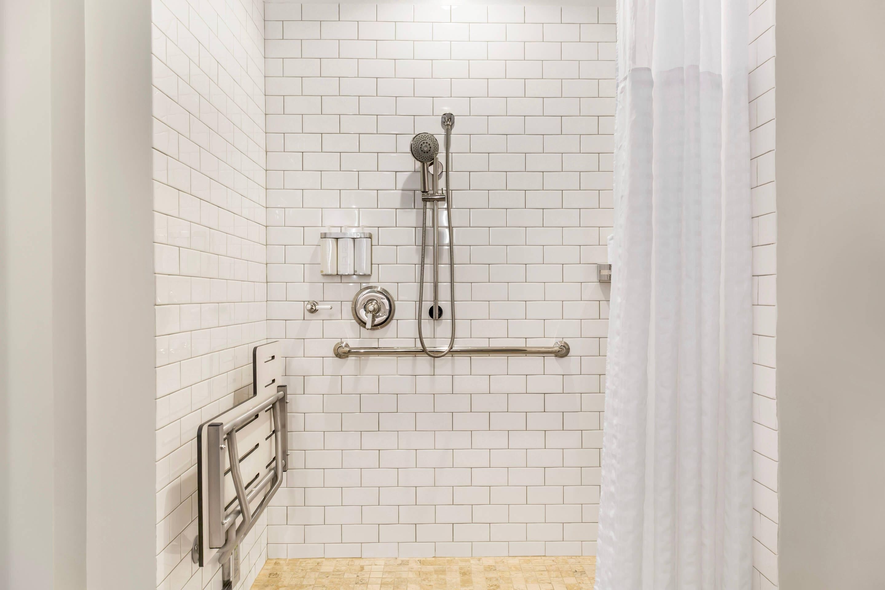 A shower with a handheld showerhead, a towel rack, and a grab bar.