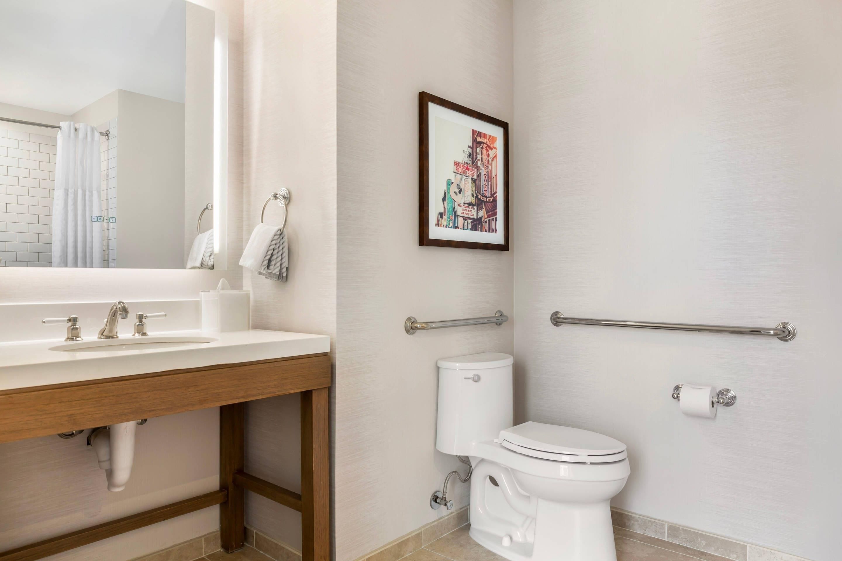 A bathroom with a white sink, toilet, and a framed picture on the wall.