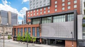 A modern hotel with a red facade, large windows, and a clear view of the street. - Cambria Hotel Nashville Downtown (Nashville)