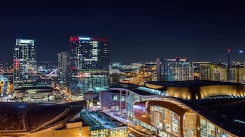Un paisaje urbano nocturno con edificios iluminados, incluyendo un edificio curvo destacado con fachada de vidrio y un cartel que dice 'Aquatic Style Arena'.