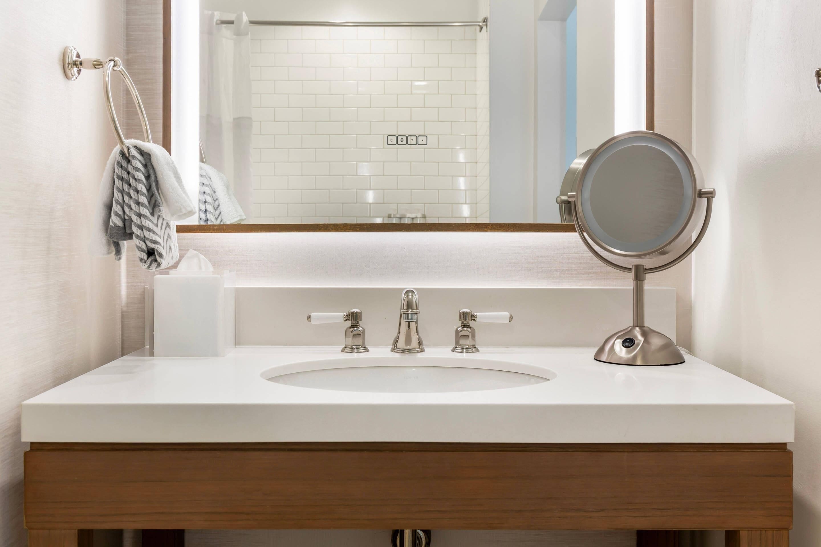 A bathroom with a white sink, two faucets, a mirror, and a towel rack.