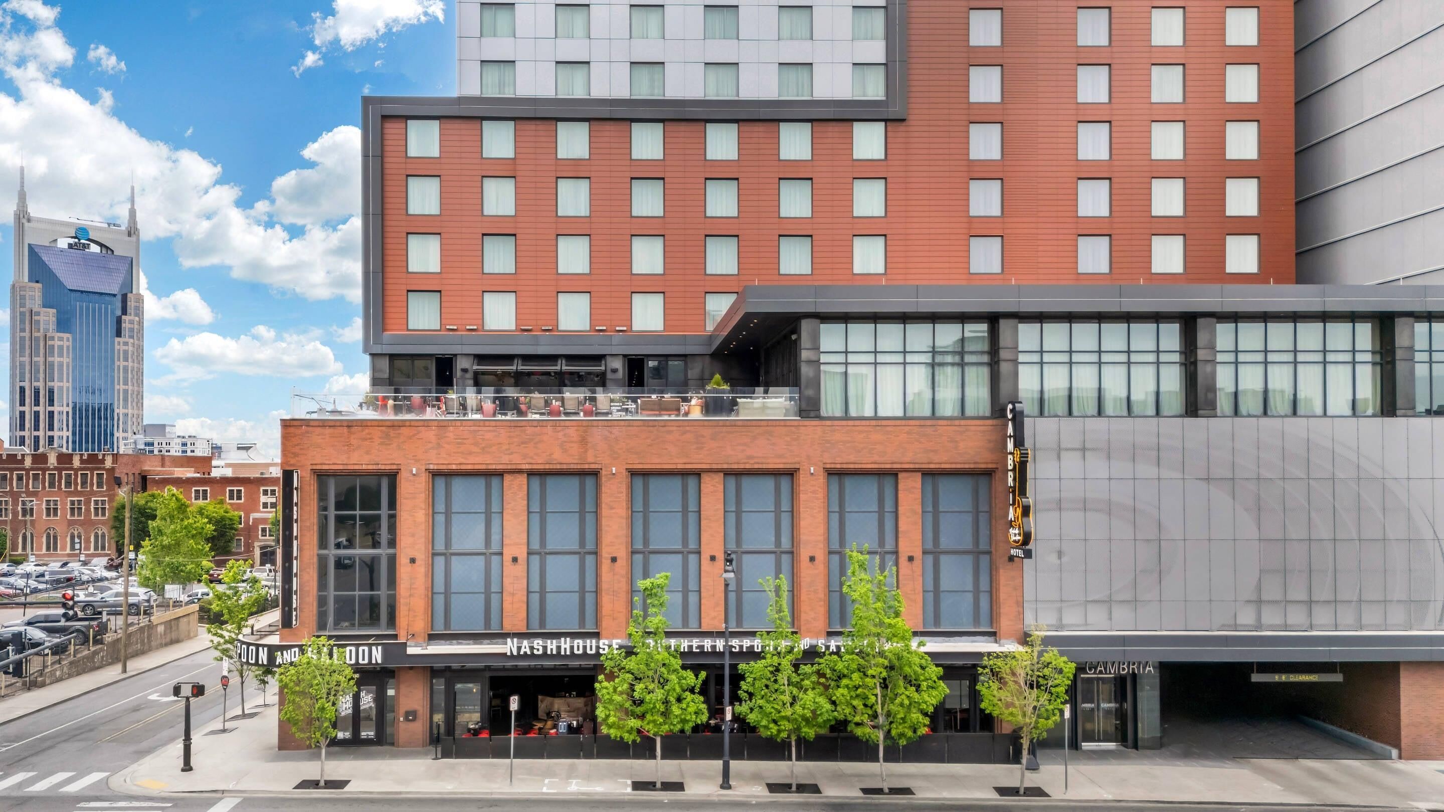 A modern hotel with a prominent entrance, large windows, and a rooftop terrace.