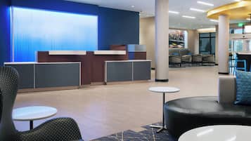 En hotellobby med en receptionsdisk, sittgrupper och ett stort fönster med utsikt.