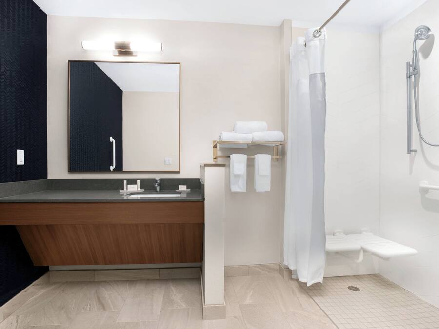 Ein modernes Badezimmer mit einem Holzwaschtisch, einem großen Spiegel und einer Duschkabine mit Glastür.