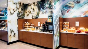 A modern hotel reception area with a marble wall, wooden reception desk, and a coffee station. - Fairfield Inn & Suites by Marriott Daytona Beach Speedway/Airport (Daytona Beach)
